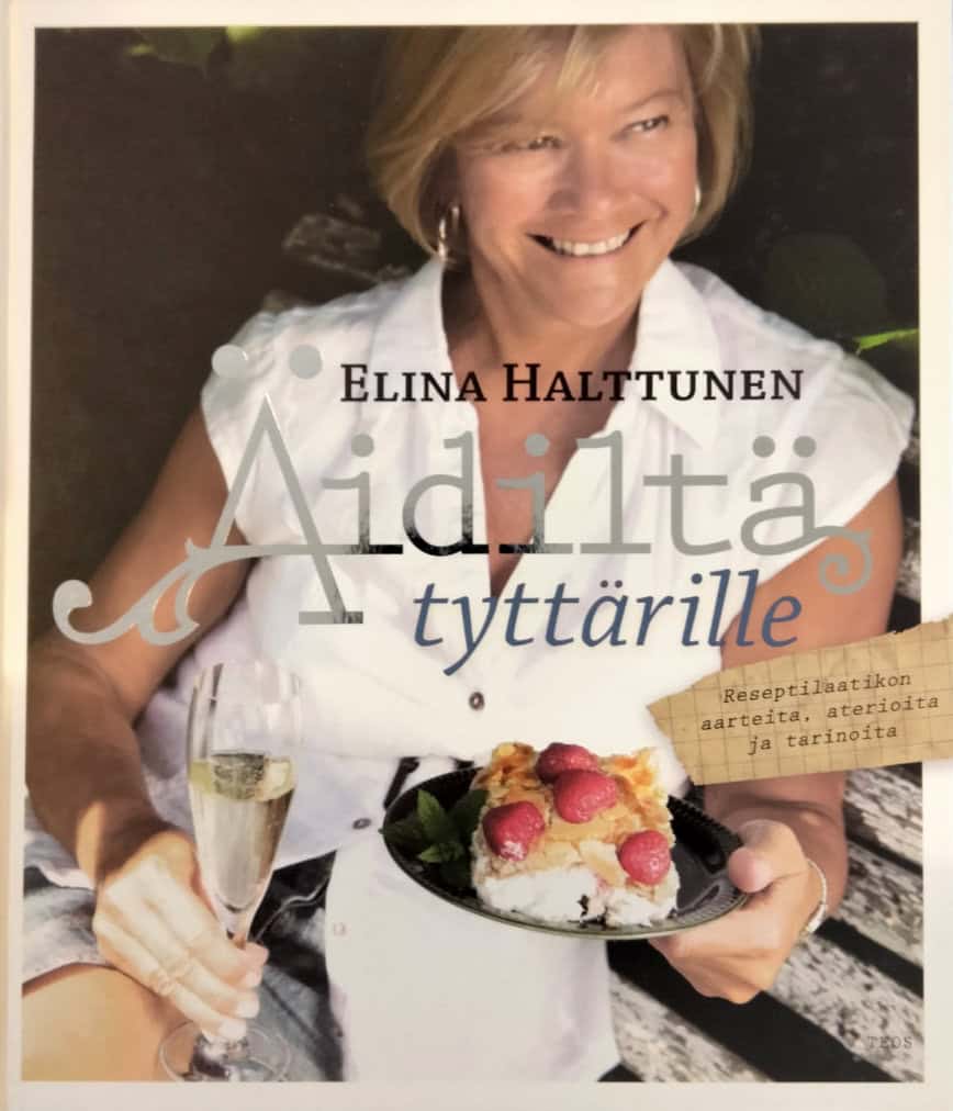 Äidiltä tyttärille -kirjna kannessa on hymyilevä nainen, jolla on toisessa kädessä kuohuviinilasi ja toisessa lautasella kakkua.