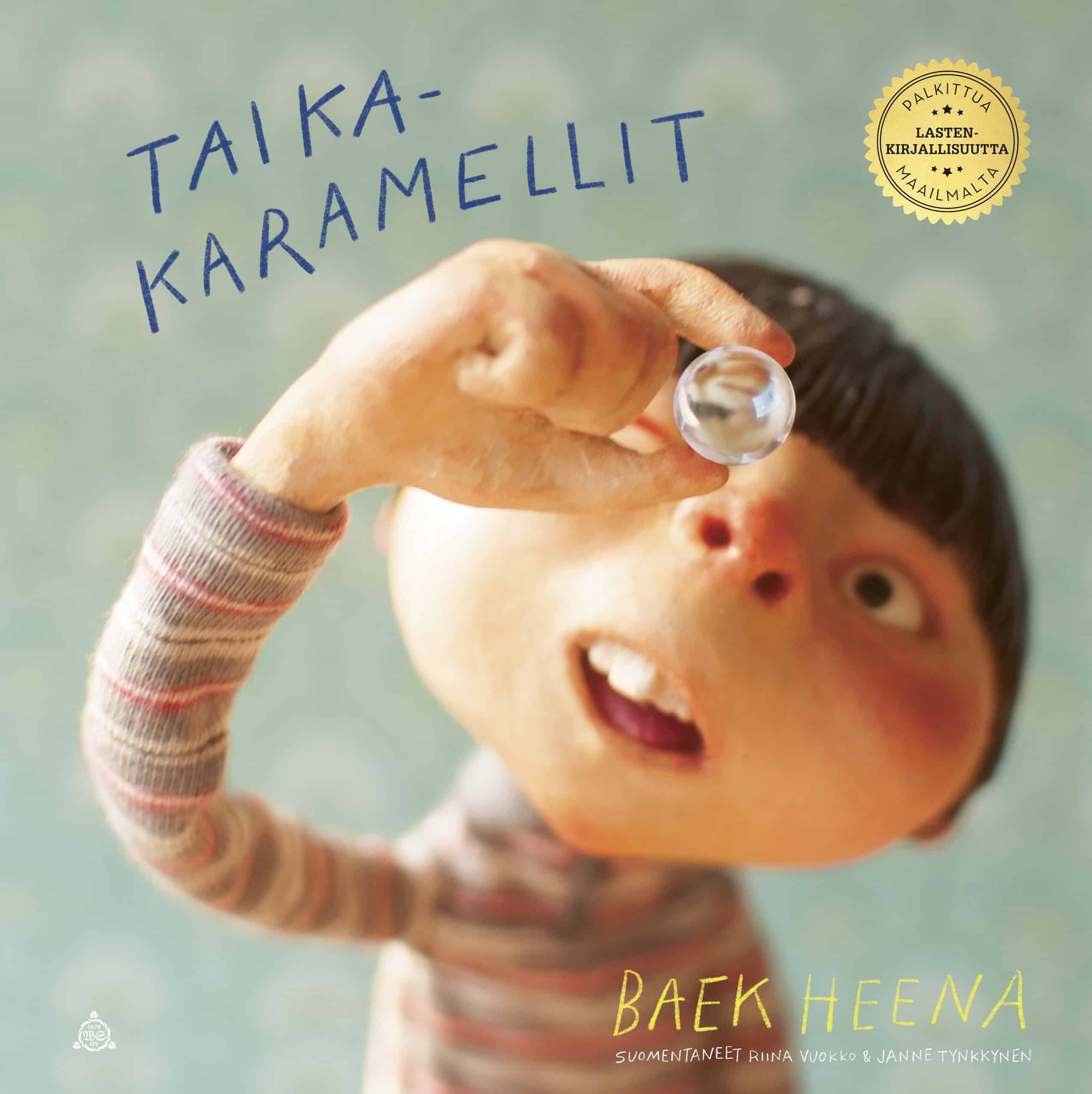 Taikakaramellit-kirjan kannessa lapsi pitelee kädessään pientä läpinäkyvää palloa ja katselee sitä keskittyneesti. Kansi on toteutettu valokuvaamalla nukke.