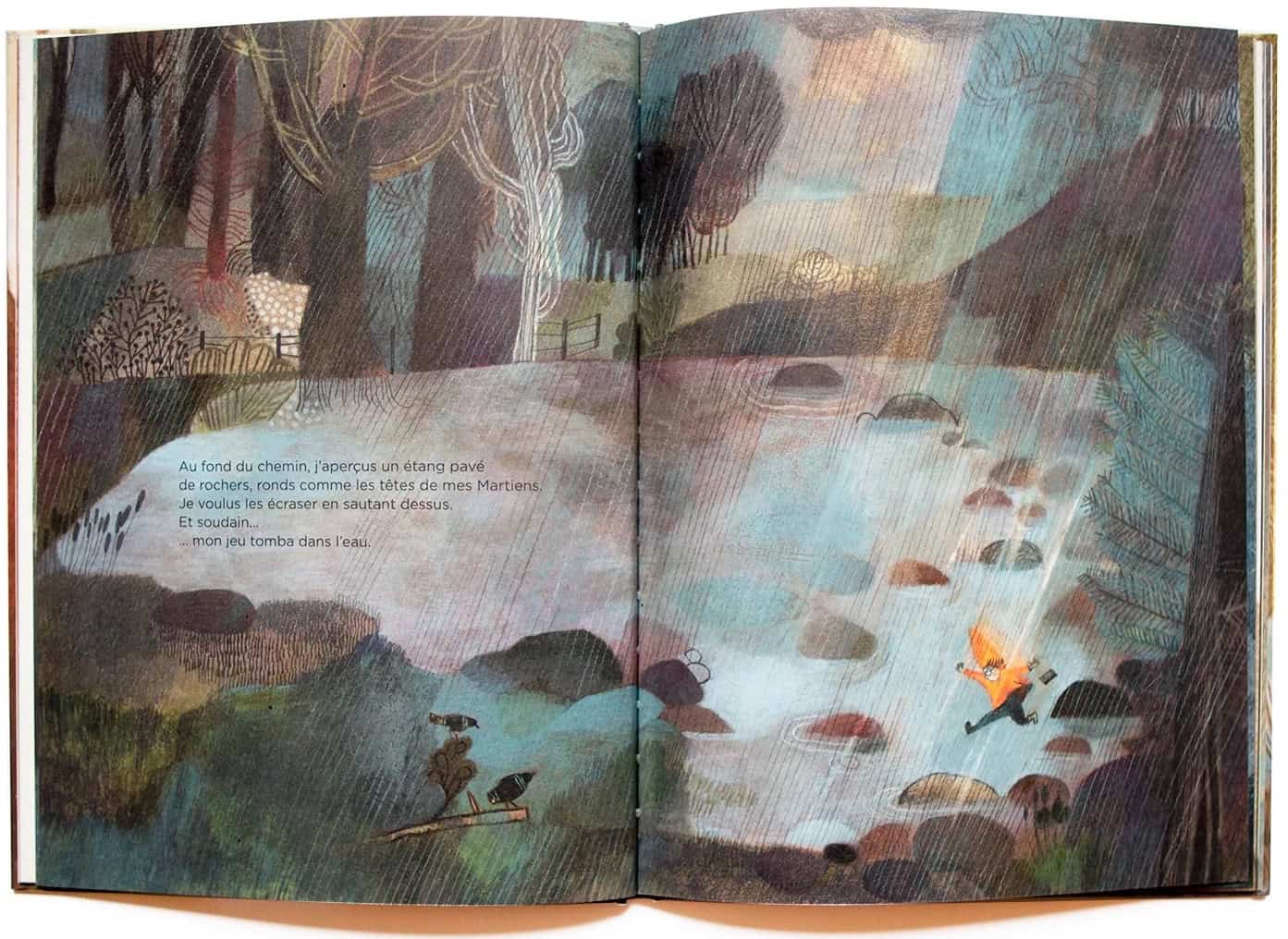 Aukeama kirjasta. Pieni oranssiin takkiin pukeutunut lapsi pomppii sateessa lammen kivillä ja pelikone putoaa taskusta. Teksti on ranskaksi. Suomeksi: "Kukkulan juurella oli lampi, josta pisti esiin kiviä, pyöreitä kuin marsilaisten päät. Ryhdyin pomppimaan niitä mäsäksi. Ja yhtäkkiä... ...peli putosi veteen."