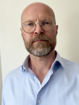 Valokuva Sami Montellista. Kuvassa on kaljupäinen, parrakas mies, jolla silmälasit ja vaaleansininen kauluspaita.